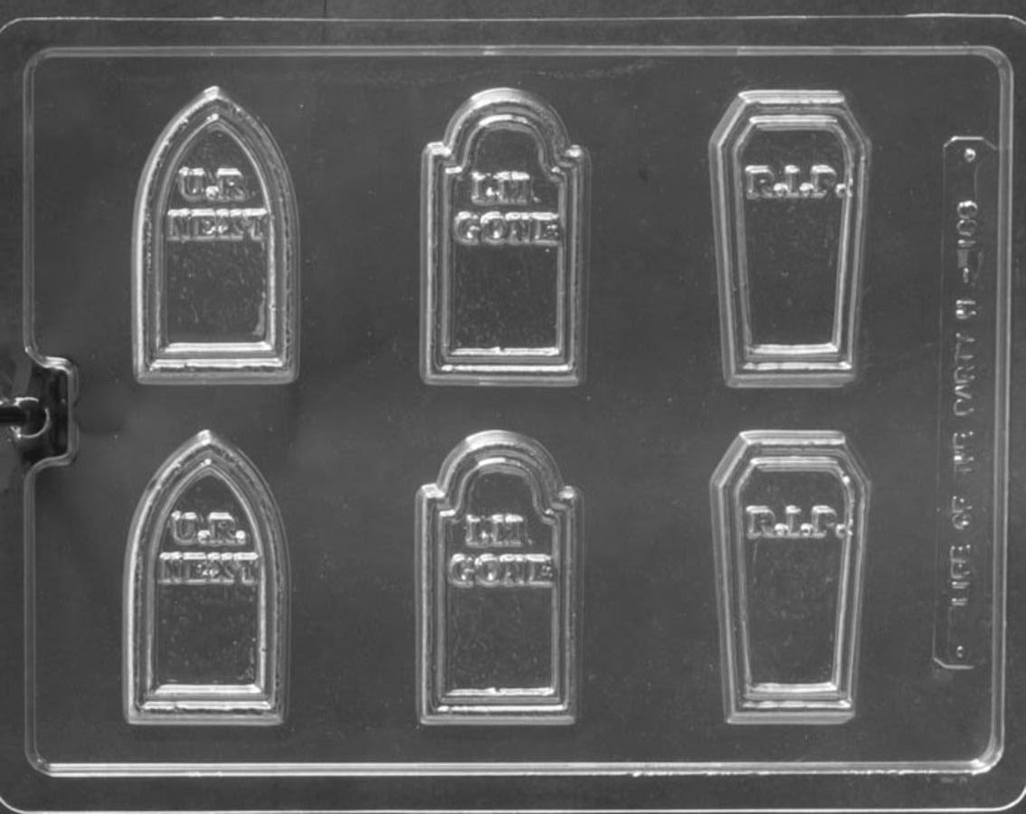 Clear plastic mold with tombstone and coffin shapes on a black background