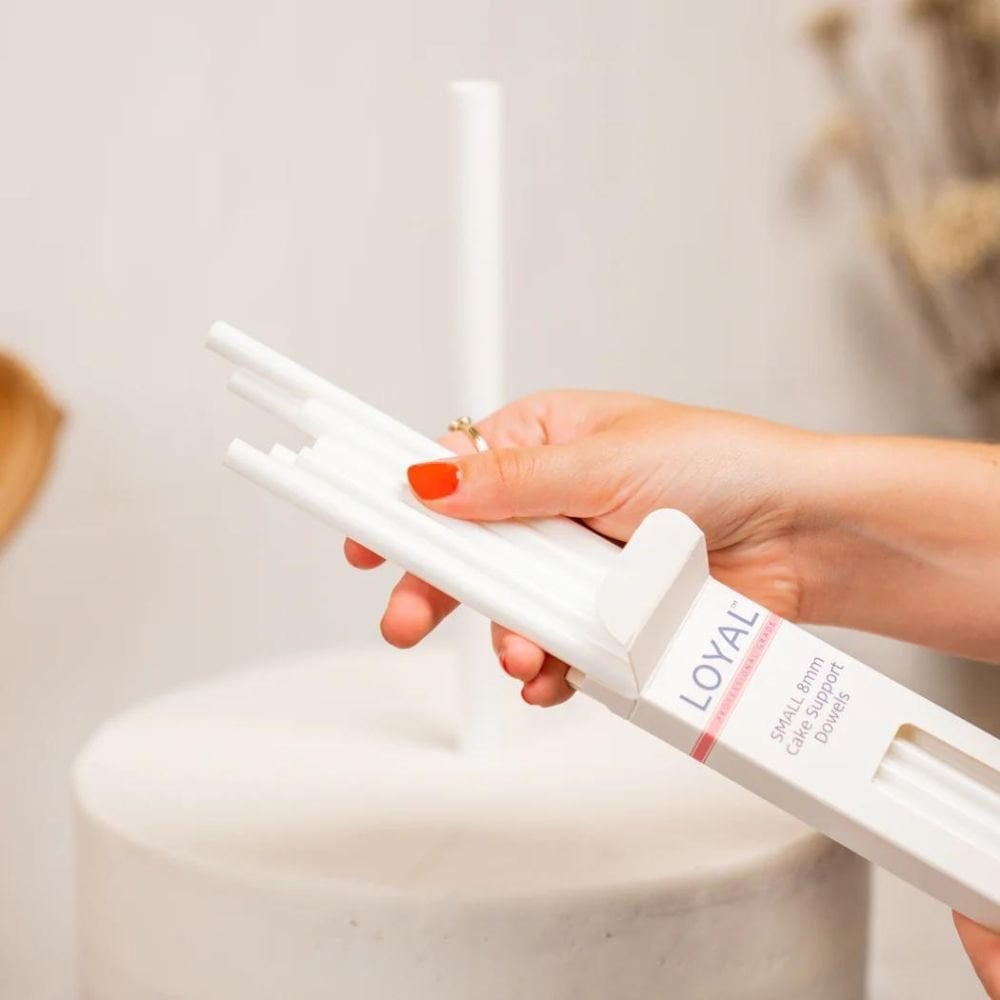 Hand holding a white cylindrical product with 'LOYAL' branding against a neutral background